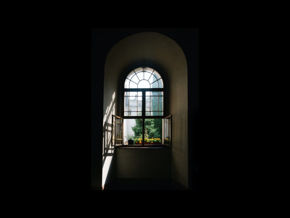 an arched window in a hallway in need of shades
